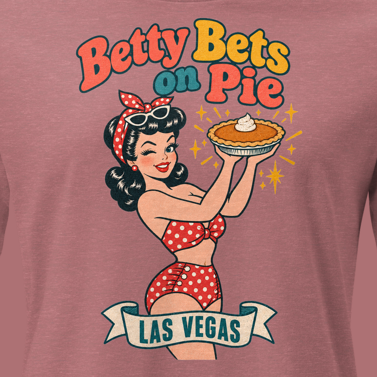 Betty Bets on Pie Relaxed T-Shirt in Heather Mauve, close-up of the front print, Downtown Betty in a polka dot swimsuit holds up a pumpkin pie like a jackpot and winks