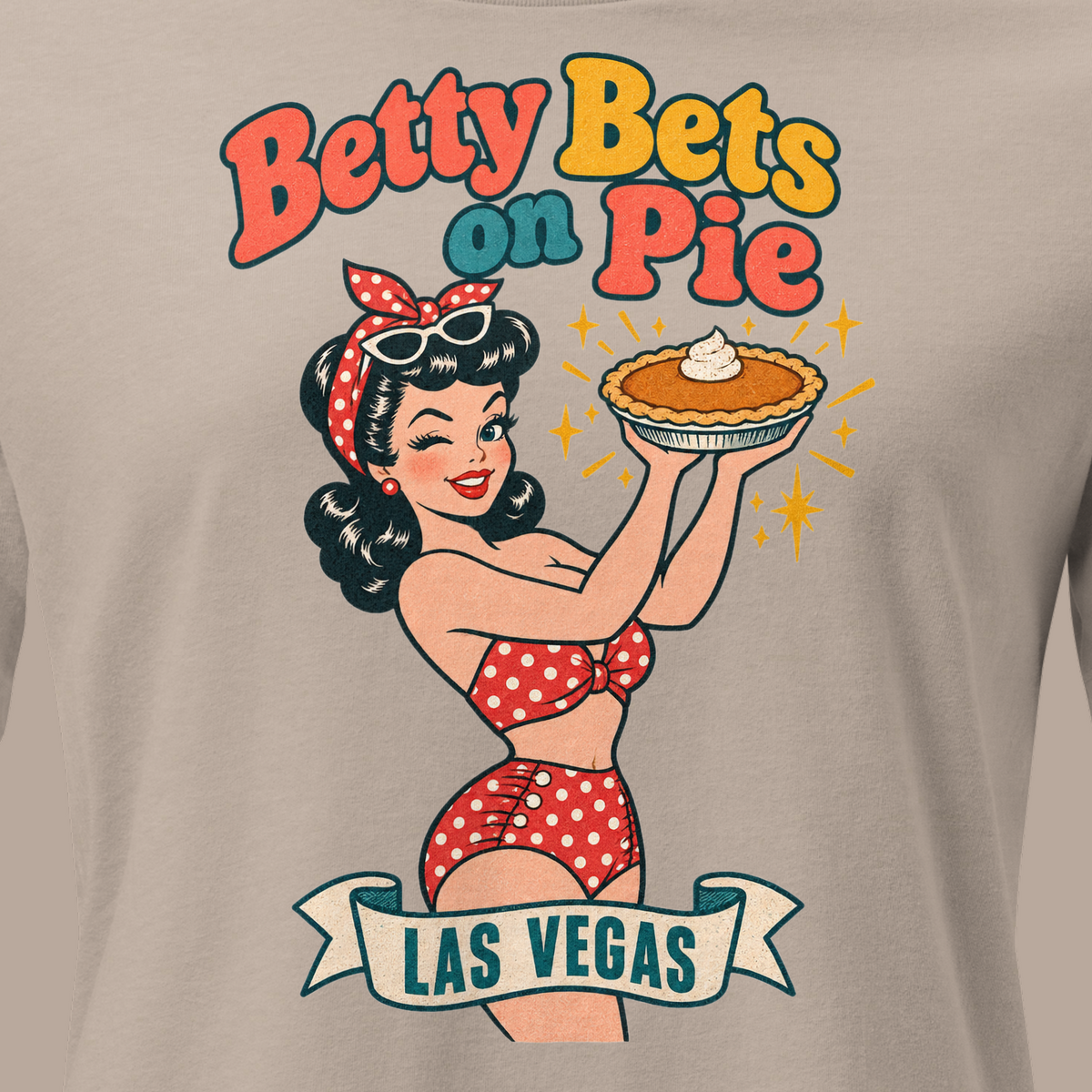 Betty Bets on Pie Relaxed T-Shirt in Heather Stone, close-up of the front print, Downtown Betty in a polka dot swimsuit holds up a pumpkin pie like a jackpot and winks