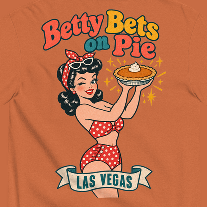 Betty Bets on Pie T-Shirt in Yam, close-up of the back print, Downtown Betty in a polka dot swimsuit holds up a pumpkin pie like a jackpot and winks